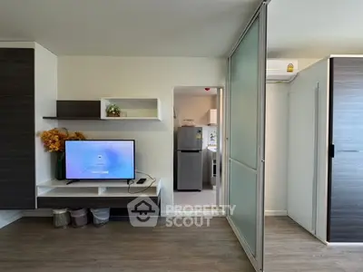 Modern living room with sliding door and view into a sleek kitchen area