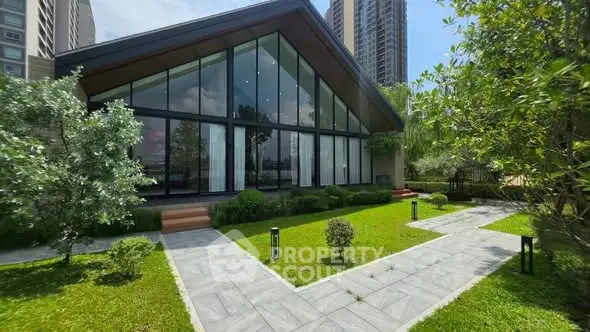 Modern architectural home with expansive glass facade and lush green garden
