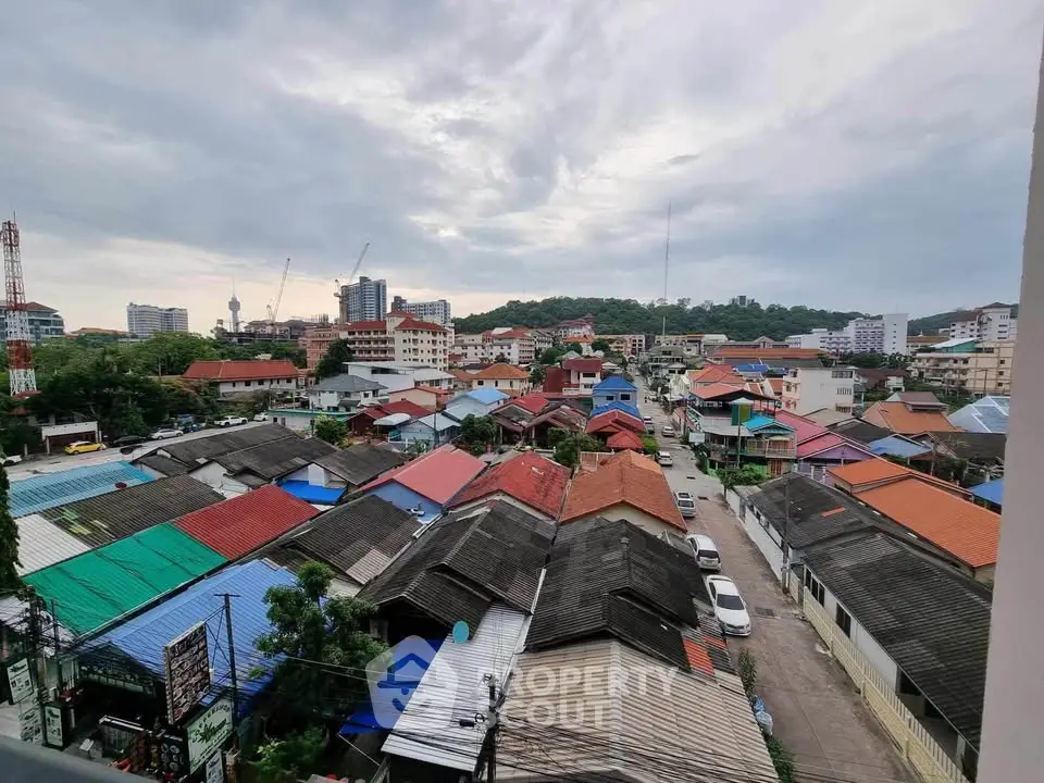 Scenic cityscape view showcasing colorful rooftops and urban skyline under a cloudy sky.