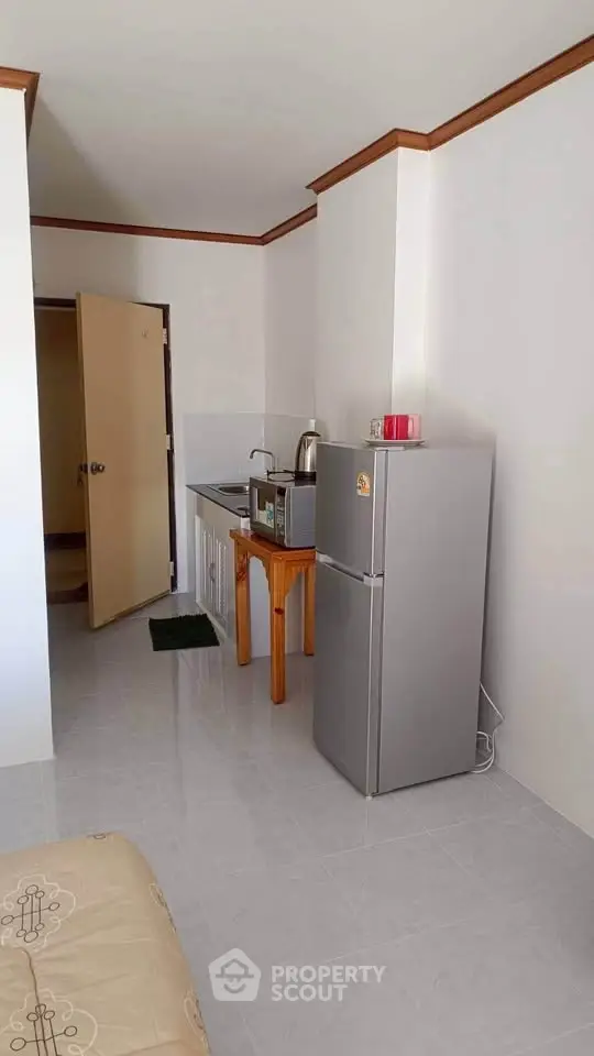 Compact kitchen area with fridge and microwave in a cozy apartment