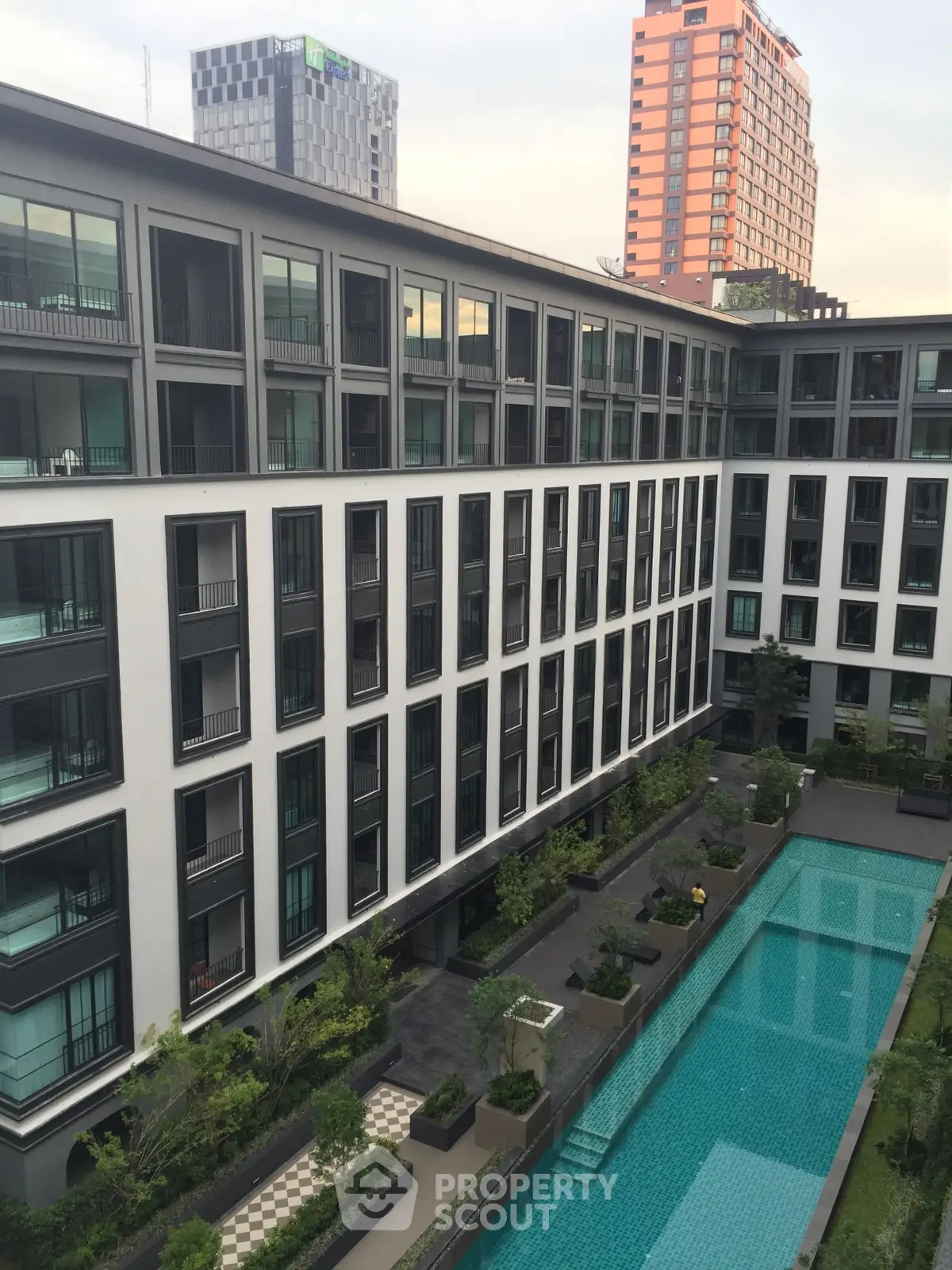 Modern apartment building with a luxurious swimming pool and lush greenery, perfect for urban living.