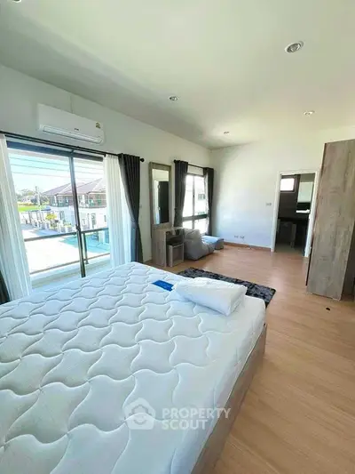 Spacious bedroom with large windows and modern decor in a bright home.