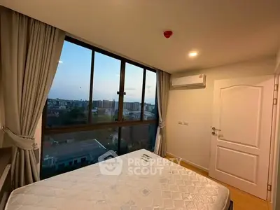 Bright bedroom with large window offering city view, featuring a comfortable bed and air conditioning.