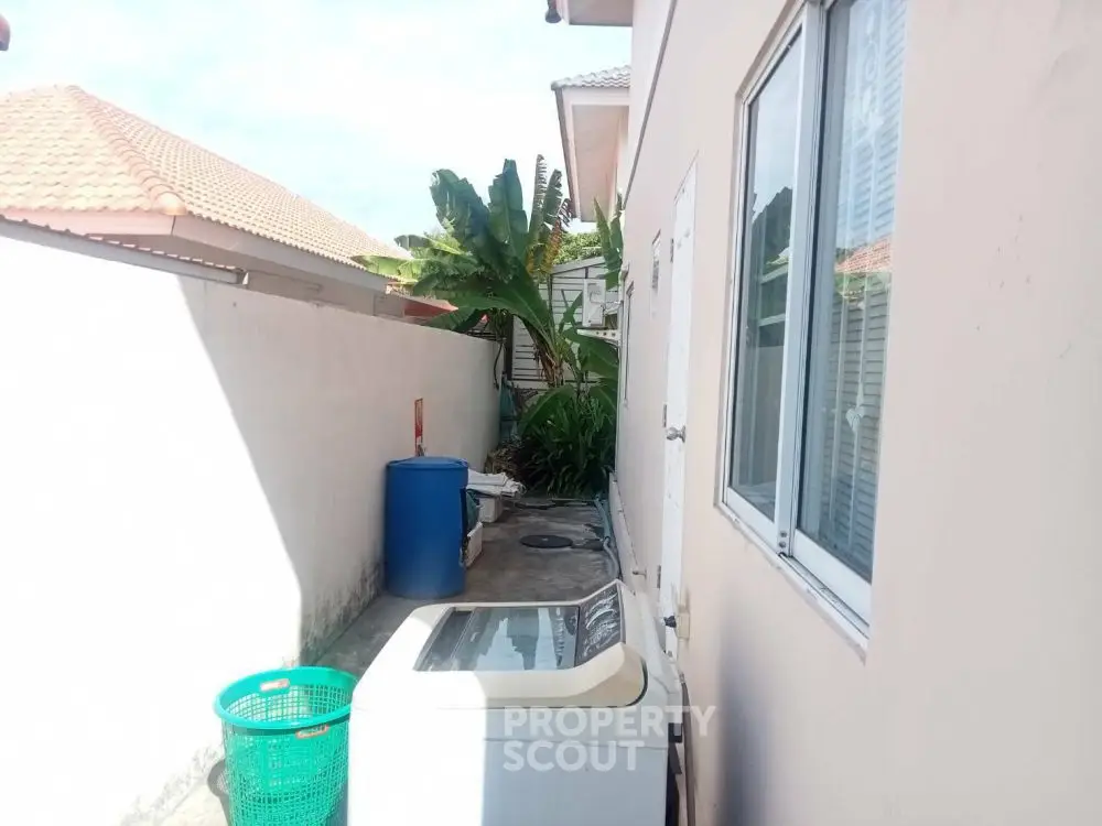 Outdoor laundry area with washing machine and tropical plants