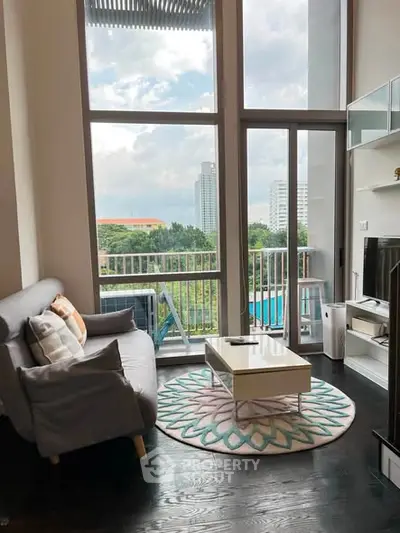 Modern living room with high ceilings, large windows, and balcony view in urban apartment.