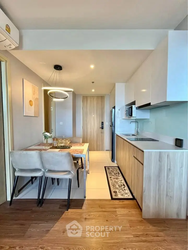 Modern kitchen with dining area, sleek cabinetry, and stylish lighting in a cozy apartment.