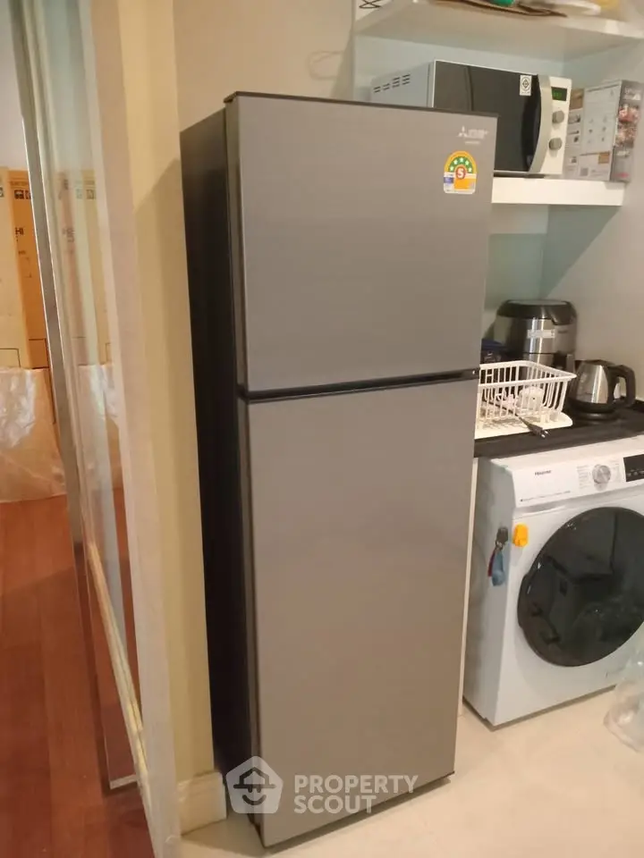 Modern kitchen with sleek fridge, washing machine, and microwave in compact layout.