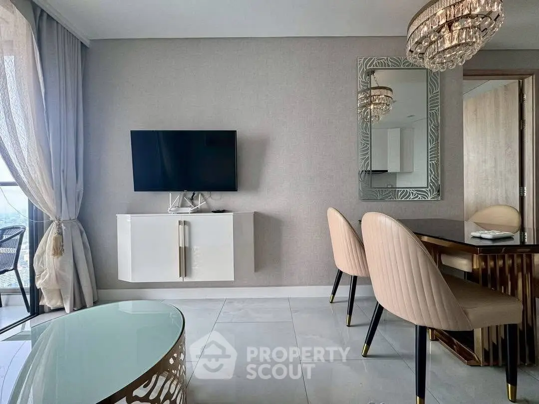 Luxurious living room with elegant decor and modern furniture, featuring a wall-mounted TV and chic chandelier.