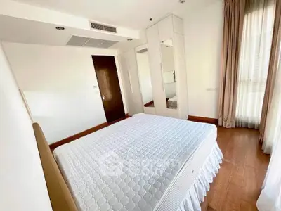 Spacious bedroom with wooden flooring and large windows in modern apartment