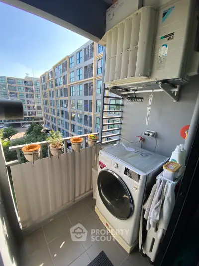 Modern apartment balcony with washing machine and scenic view of residential complex.