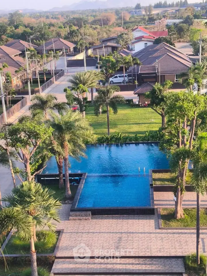 Stunning aerial view of a luxurious residential pool surrounded by lush greenery and modern homes.