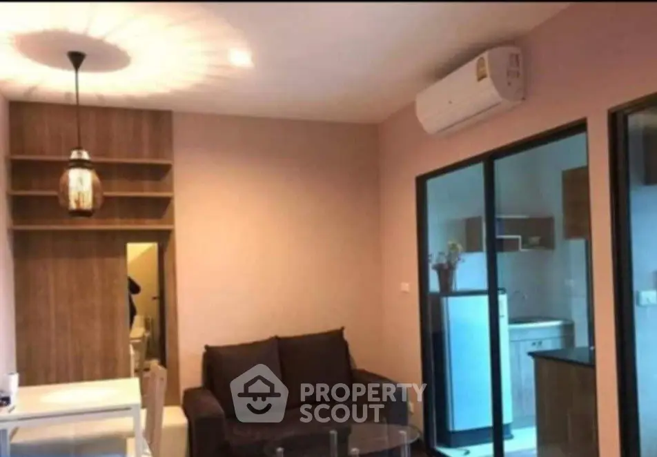 Modern living room with stylish lighting and air conditioning, adjacent to a sleek kitchen.