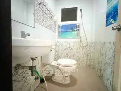 Charming bathroom with beach-themed window decal and modern fixtures.