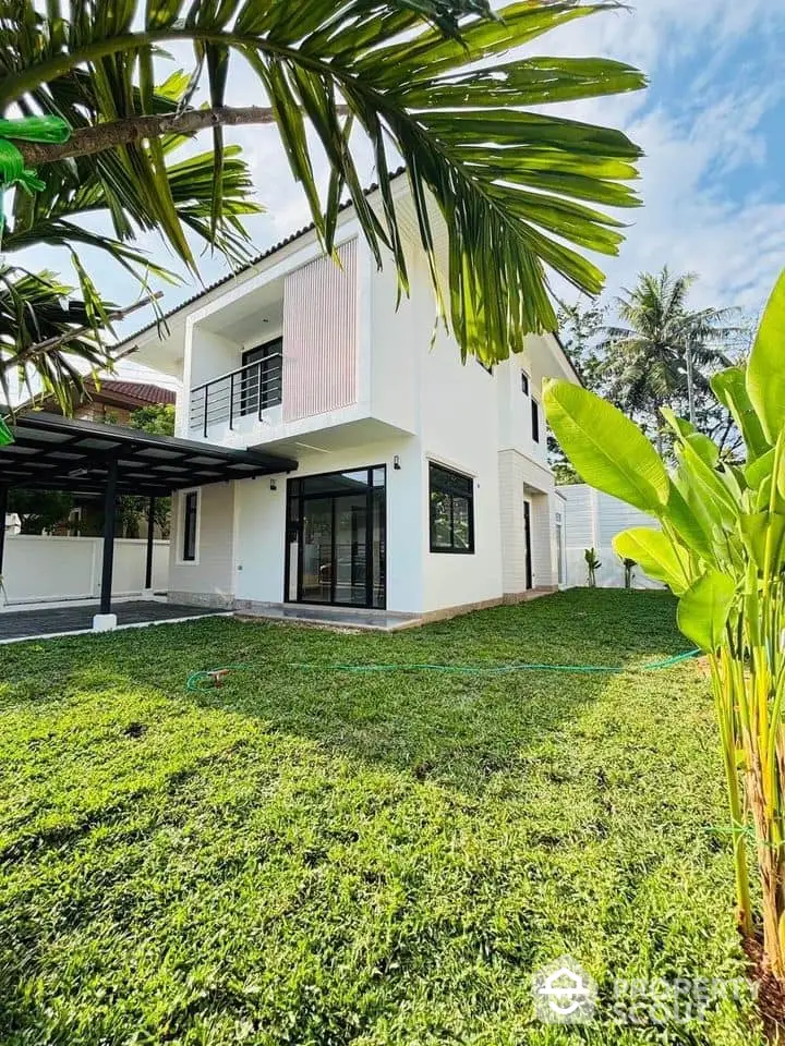 Modern two-story house with lush green lawn and tropical landscaping