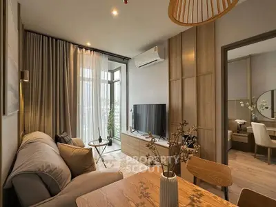 Modern living room with stylish decor and natural light, featuring a cozy sofa and large TV.