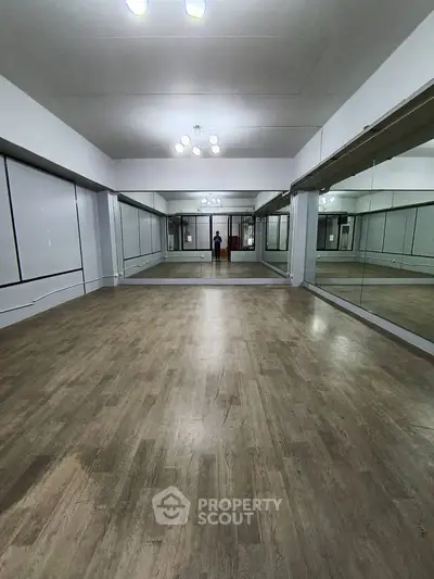 Spacious mirrored room with wooden flooring, ideal for dance or fitness studio.