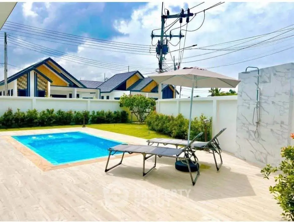 Luxurious outdoor pool area with sun loungers and shower, perfect for relaxation and entertainment.