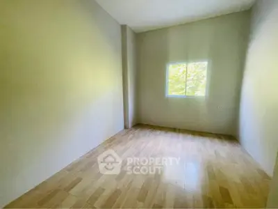 Spacious empty room with wooden flooring and large window, perfect for customization.