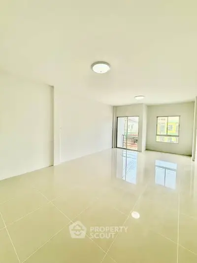 Spacious and bright living room with large windows and glossy tiled floors.
