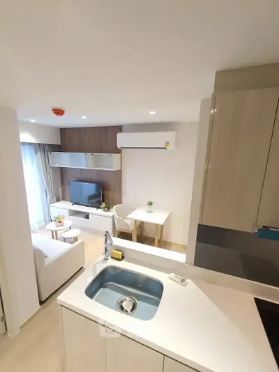 Modern open-layout living room with kitchen, featuring sleek design and cozy ambiance.