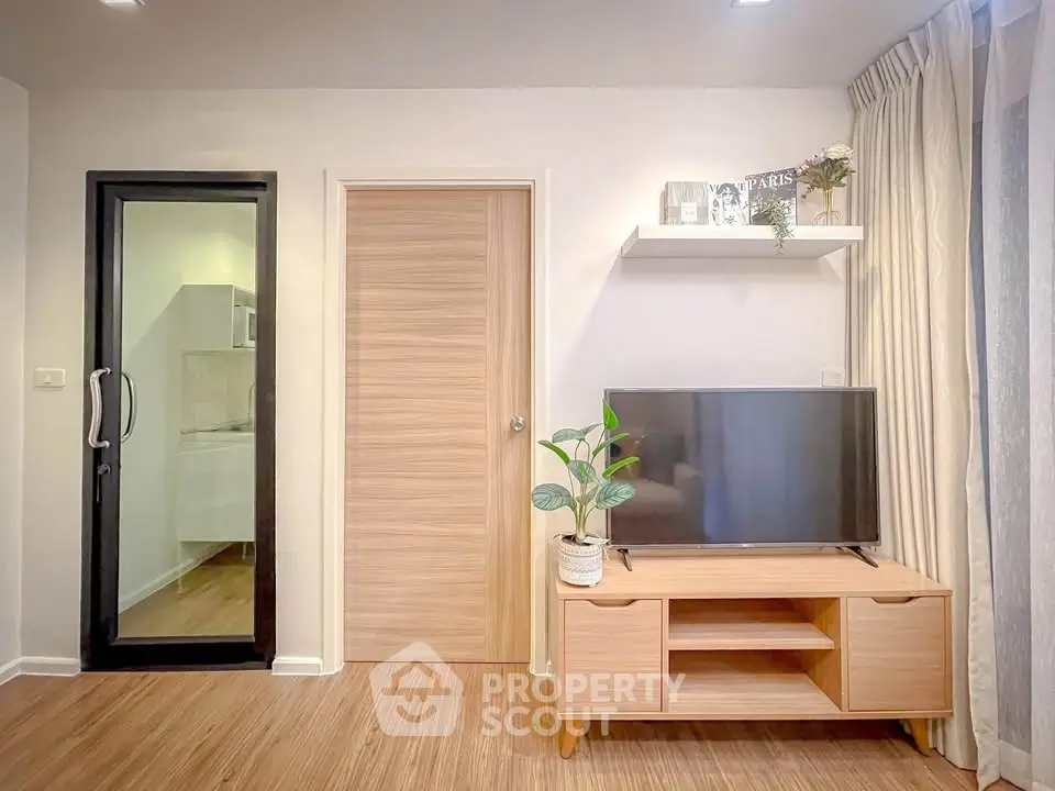 Modern living room with wooden TV stand and glass door to kitchen