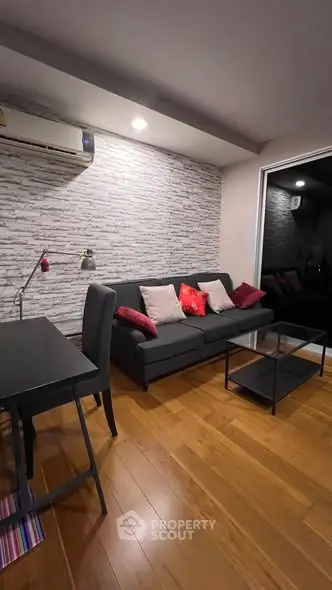 Modern living room with stylish decor and cozy seating area, featuring a sleek black sofa and elegant wooden flooring.