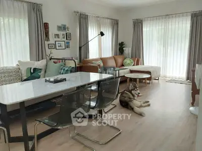 Spacious living room with modern decor and natural light, featuring a cozy seating area and stylish dining table.