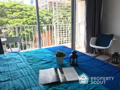 Bright bedroom with balcony view, featuring cozy decor and lush greenery outside.