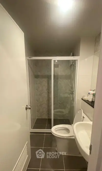 Modern bathroom with glass shower and sleek fixtures in contemporary apartment.