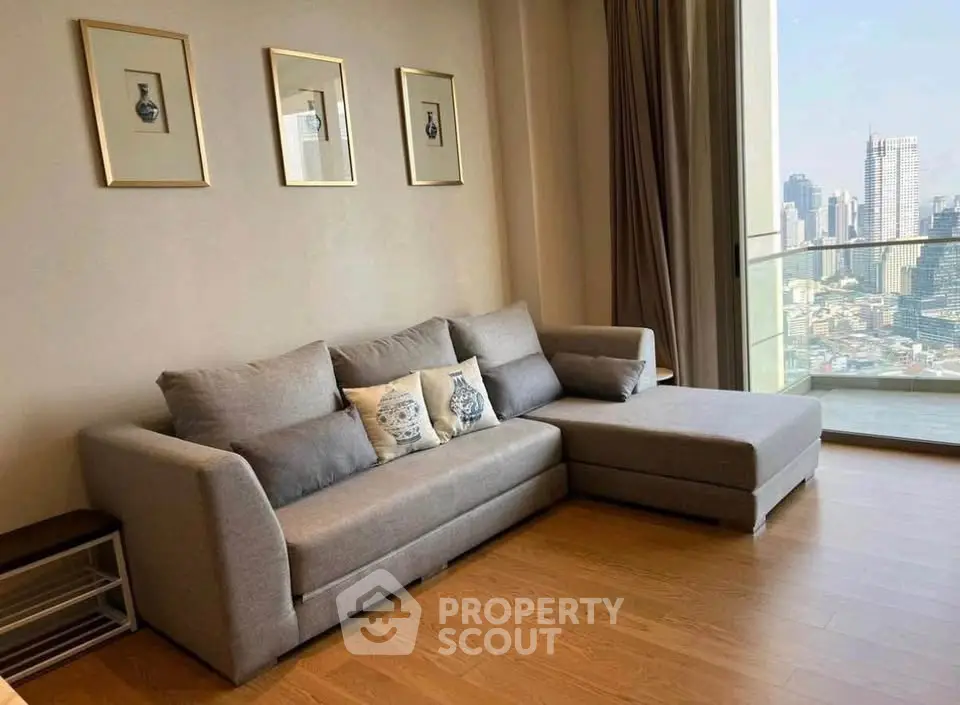 Modern living room with stylish gray sofa and city view balcony in high-rise apartment.