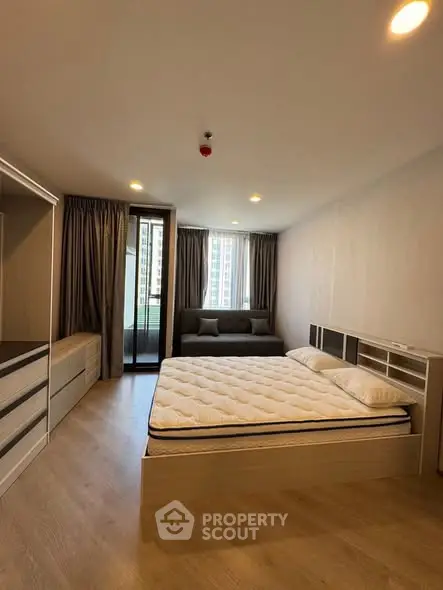 Spacious modern bedroom with large windows and balcony access in a high-rise apartment.