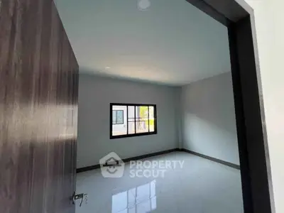Spacious empty room with large window and sleek flooring, perfect for customization.