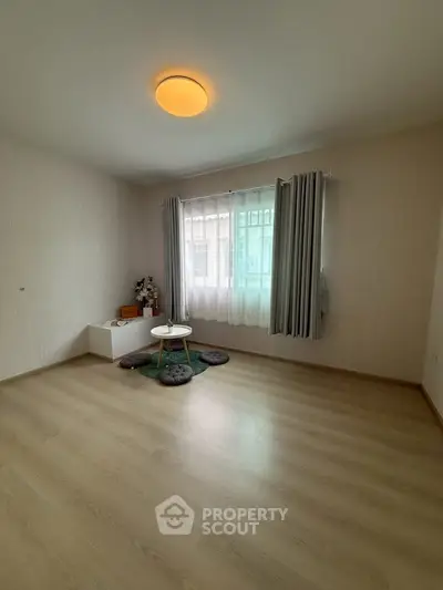 Spacious minimalist room with large window and wooden flooring, perfect for versatile living arrangements.