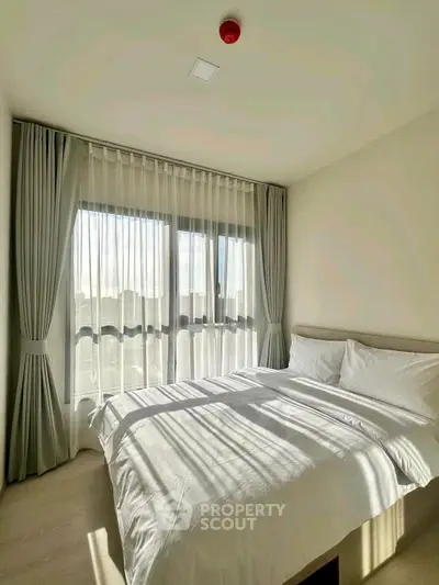 Bright and airy bedroom with large windows and elegant curtains, perfect for a serene retreat.