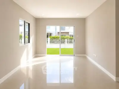 Spacious empty room with large windows and garden view, perfect for customization.