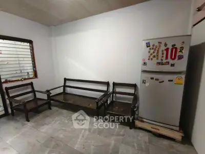 Spacious room with wooden seating and a refrigerator, ideal for versatile use.