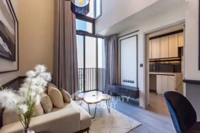 Modern living room with high ceilings and natural light, featuring a cozy seating area and stylish decor.