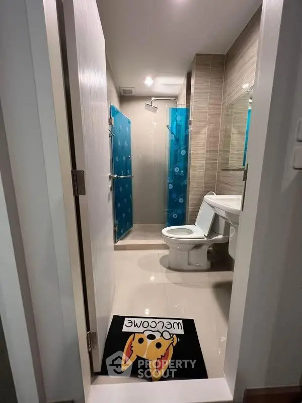 Modern bathroom with shower and toilet, featuring a playful welcome mat.