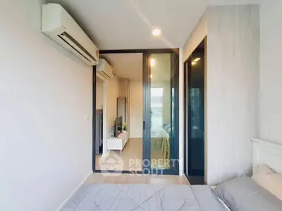 Modern bedroom with sliding glass doors leading to a stylish living area, featuring sleek air conditioning unit.