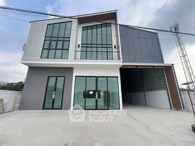 Modern industrial-style building with large glass windows and spacious garage area.