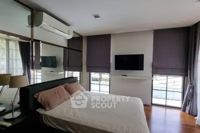 Modern bedroom with large windows and sleek design, featuring a wall-mounted TV and air conditioning.