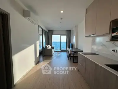 Modern open-layout living room with kitchen and large windows offering natural light.