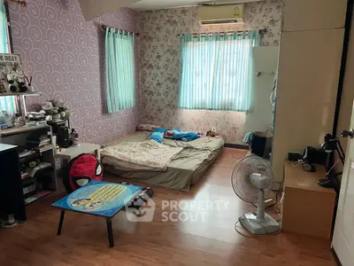 Cozy bedroom with playful decor and natural light, featuring a floor mattress and vibrant wallpaper.