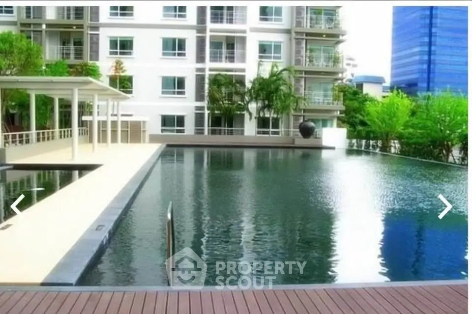 Luxurious apartment complex with serene pool and lush greenery, perfect for relaxation and modern living.