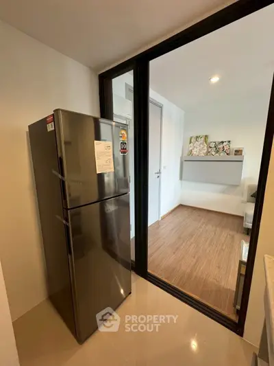 Modern apartment with sleek kitchen featuring stainless steel fridge and stylish wooden flooring.