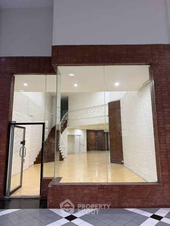 Spacious commercial property with elegant staircase and large glass facade, ideal for retail or office space.