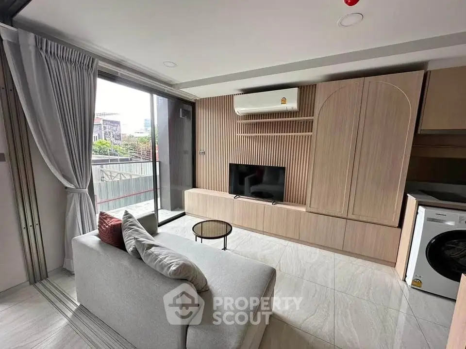 Modern living room with sleek design, featuring a cozy sofa, flat-screen TV, and large window with city view.