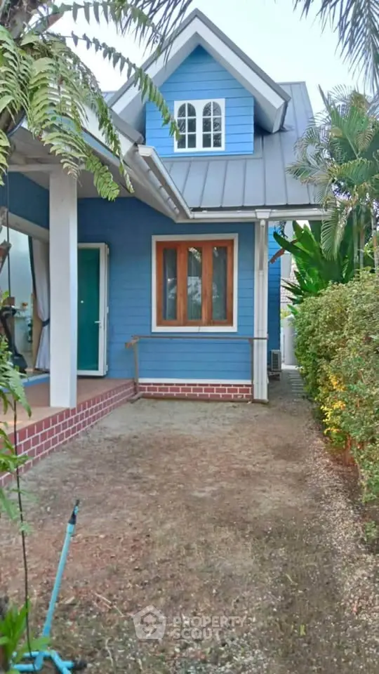 Charming blue house with lush garden and inviting entrance in serene neighborhood.