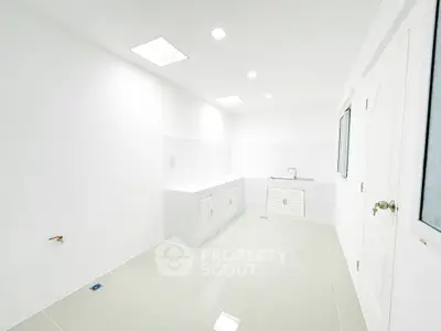 Spacious white kitchen with sleek modern design and ample storage space.