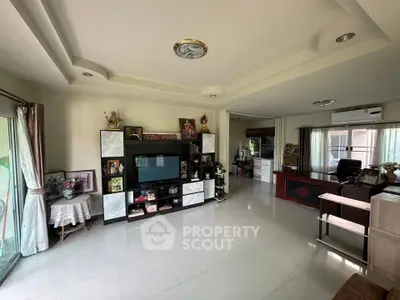 Spacious living room with modern entertainment center and large windows for natural light.